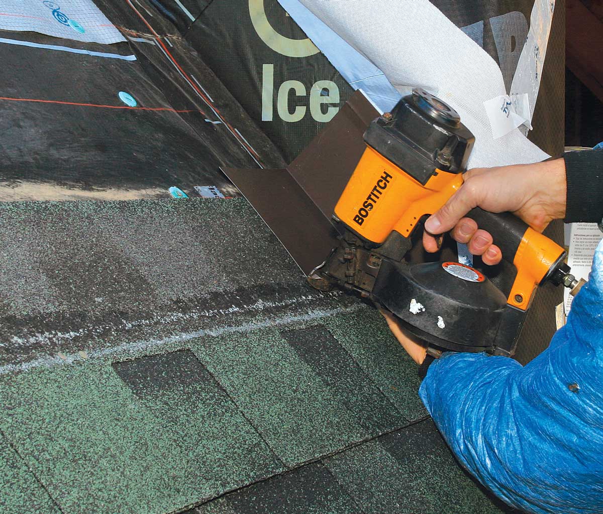Lap the step flashing over the shingle. Keep the bottom of the flashing above the shingle’s nail line, and drive one roofing nail through the outside bottom corner of the flashing.